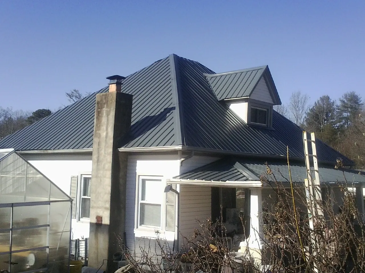 Dark blue standing seam metal roof on a white farmhouse with dormer — Slate & Tile Roof Repair by Roofing Brothers in Eaton Park