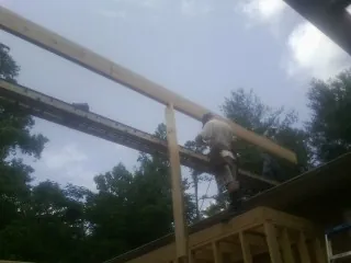 Carpenter setting a ridge beam over a new addition frame — Ice Dam Removal by Roofing Brothers in Eaton Park