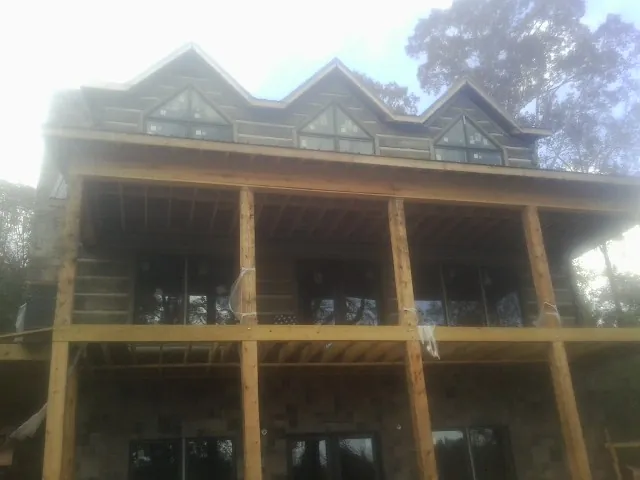 Dormers and porch framing on a large log home under construction — Roof Coating work by our crew in Eaton Park