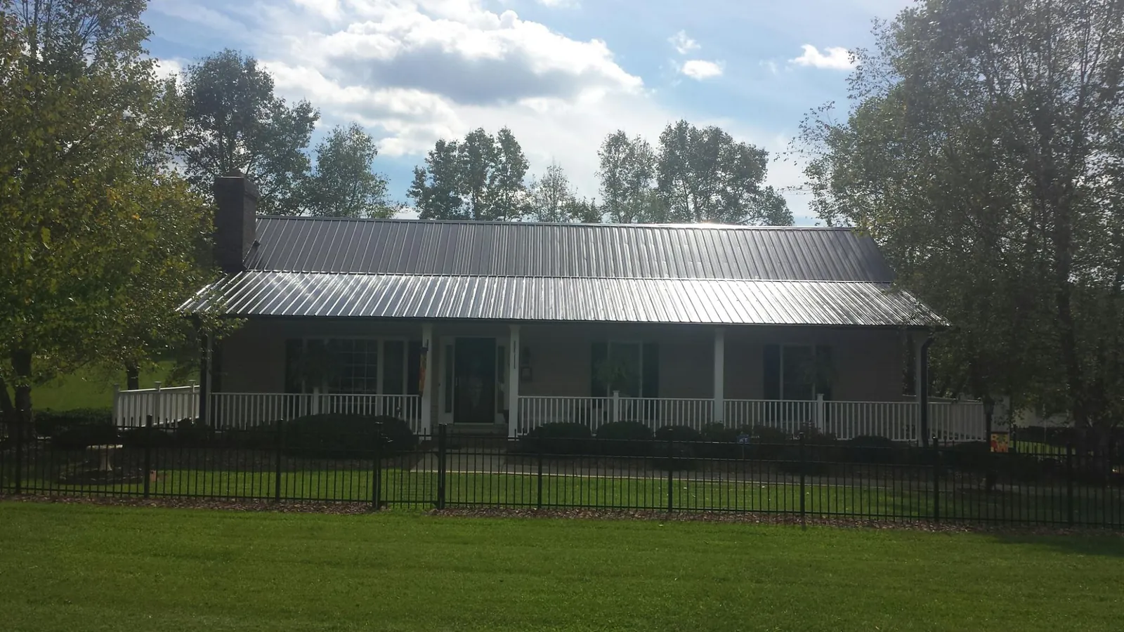 Gray metal roof on a brick ranch with a full width front porch — Gutter Guard Installation work by our crew in Eaton Park