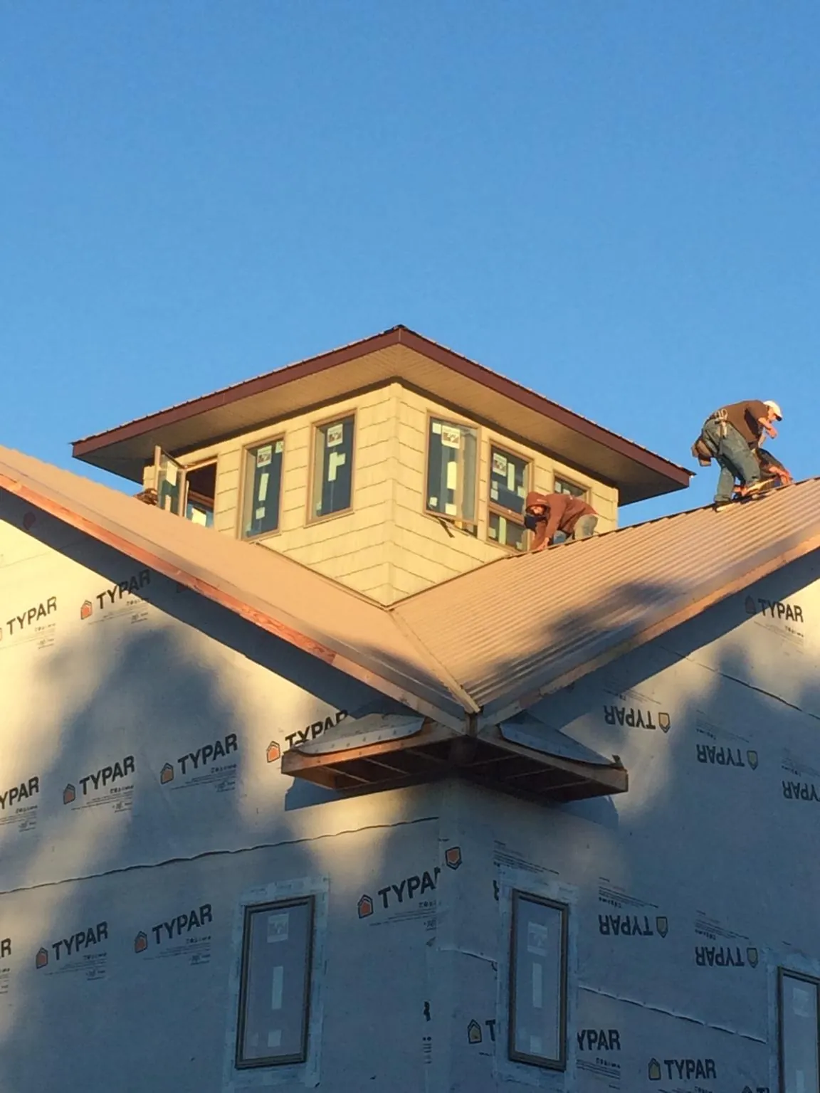 Roofers working around a rooftop cupola on a new metal roof at sunset — Roof Waterproofing in Eaton Park by Roofing Brothers